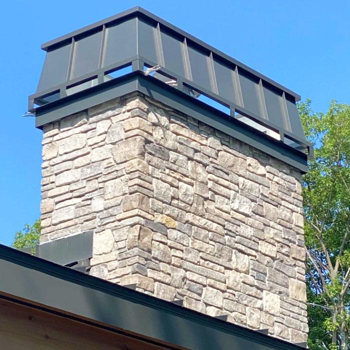 Architectural metals on the top of a stone chimney.